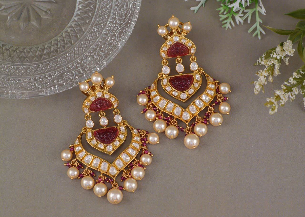 Pair of luxurious beaded earrings with pearls and gold accents on a gray surface.