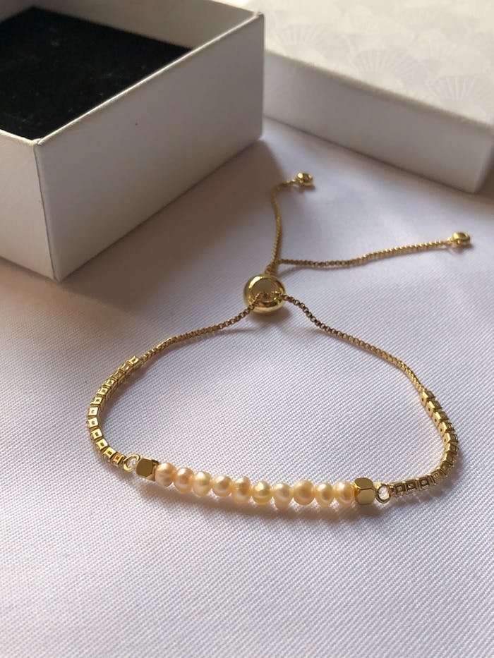 Minimalist bracelet with delicate pearls and gold chain, perfect for chic fashion.