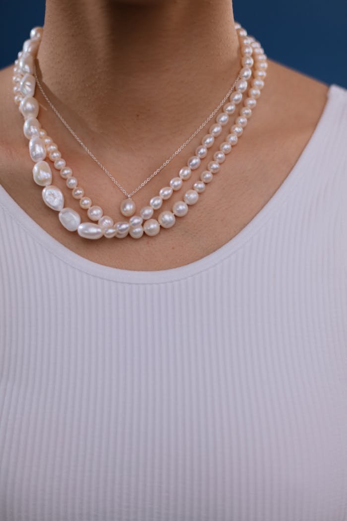 Close-up of a classic pearl necklace on a white ribbed top, offering elegance and simplicity.